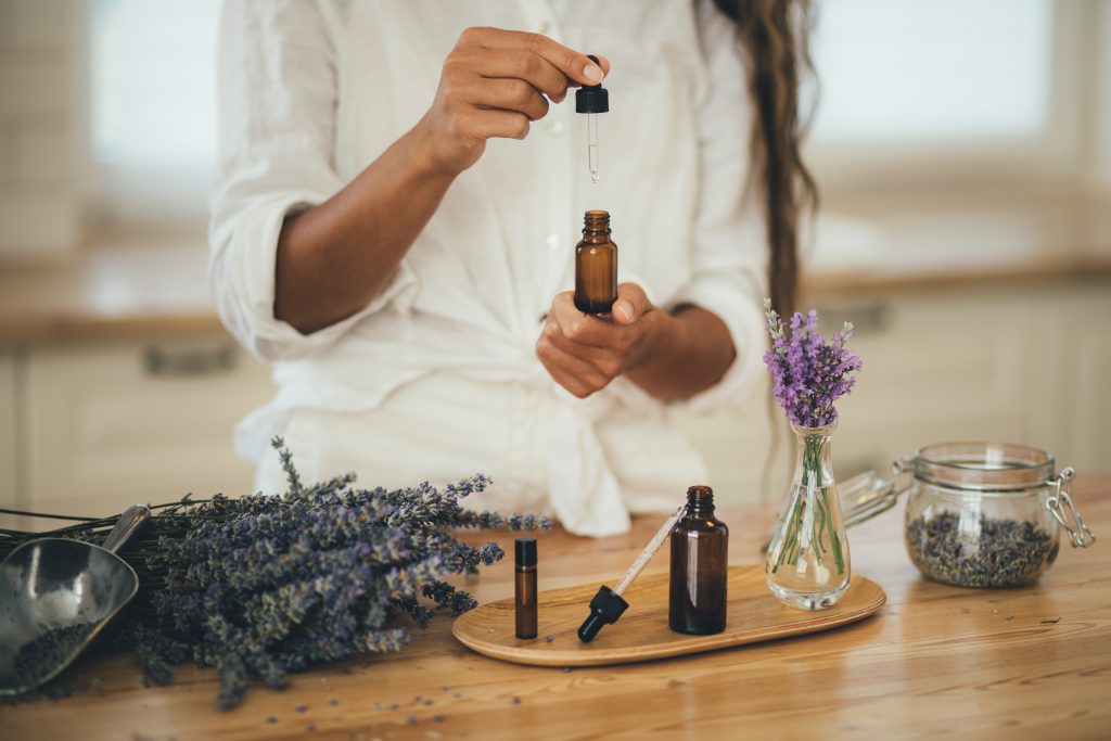 Young Woman Applying Natural Organic Essential Oil On Hair And S